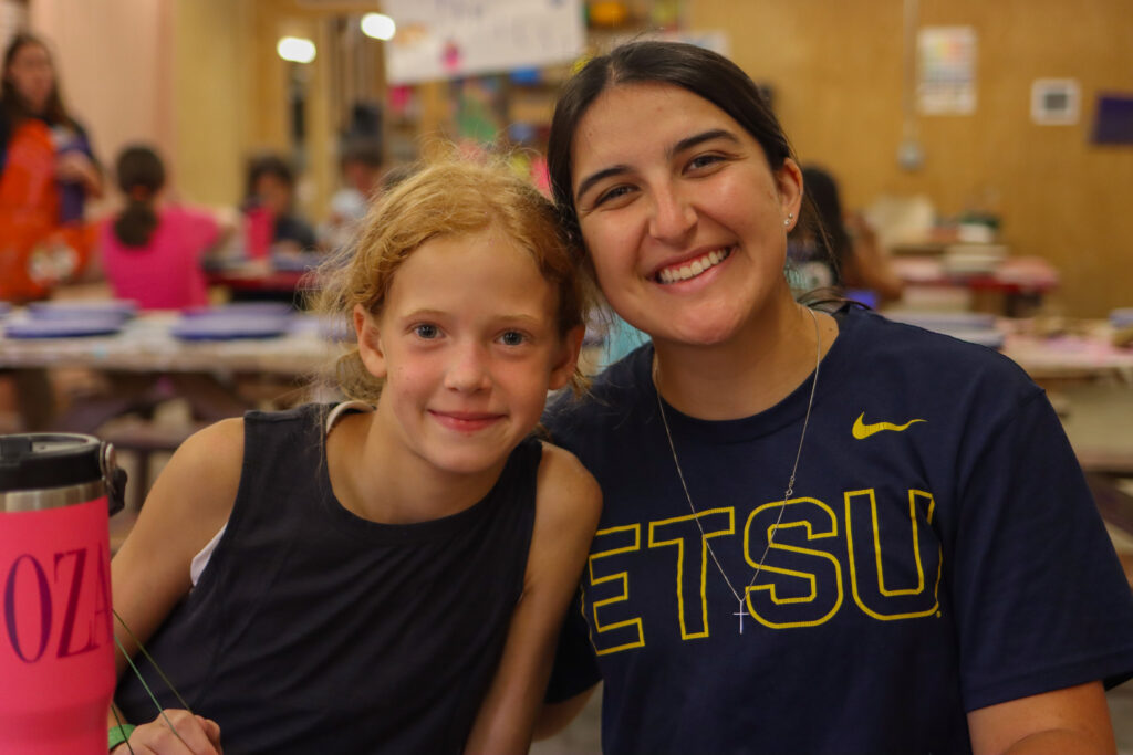 East Tennessee State student smiling with a camper at summer camp.