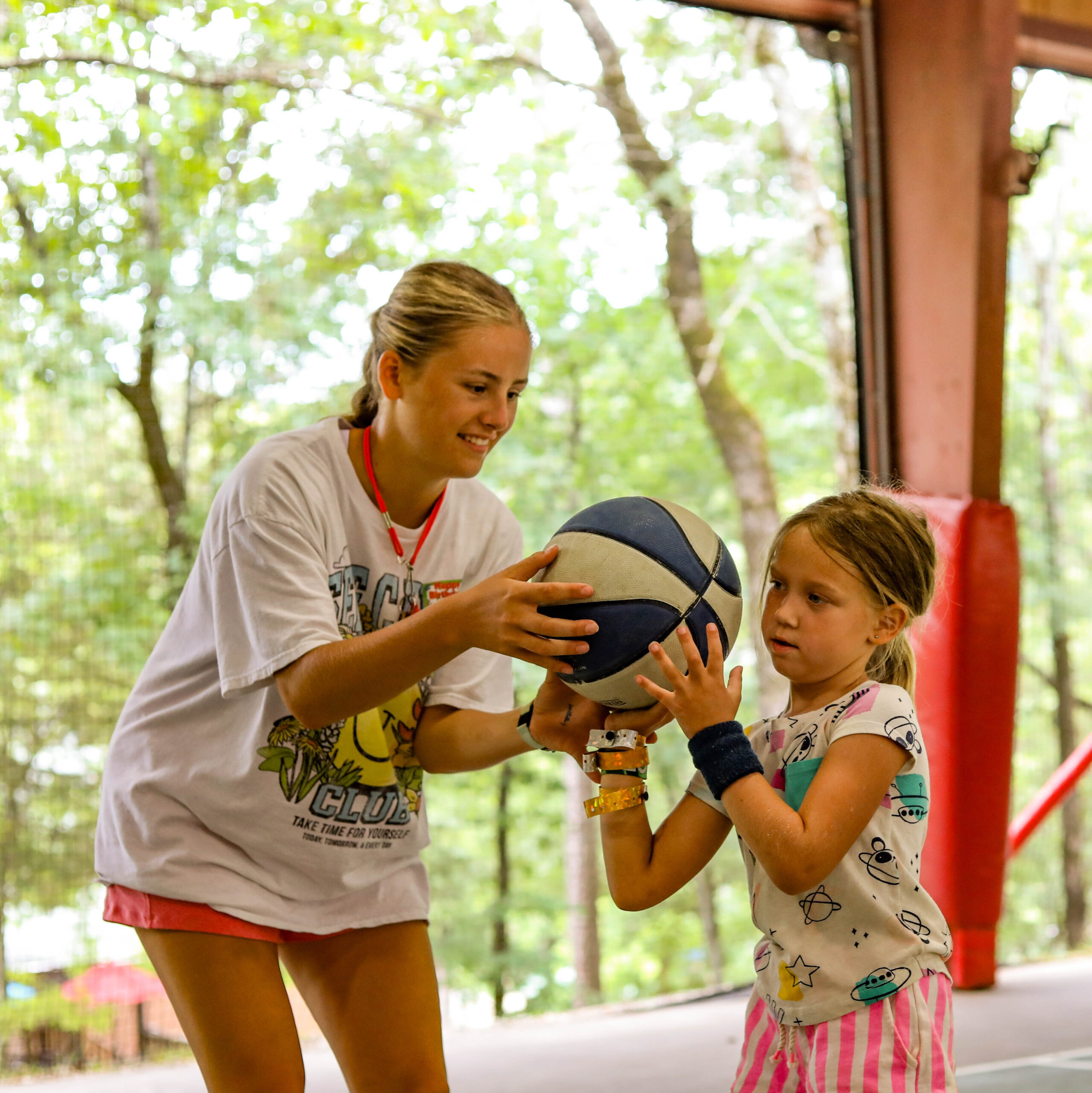 Southern Arkansas student teaching a camper to play basketball at summer camp.